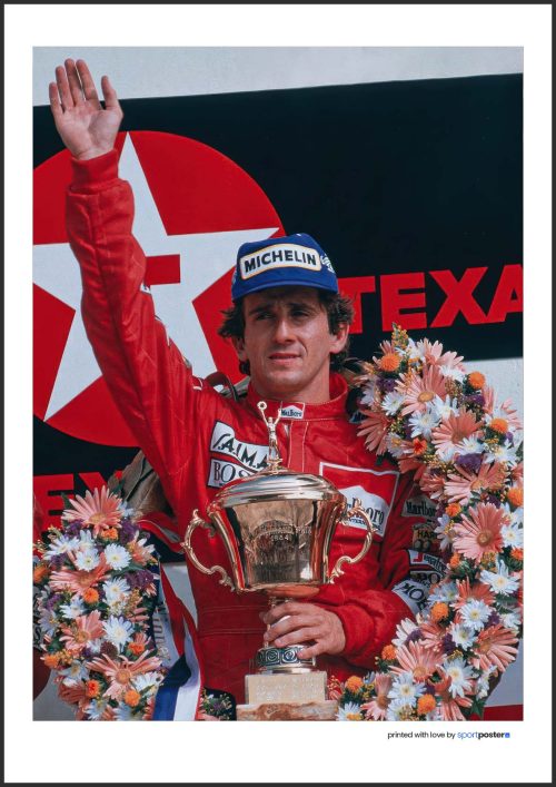 Víťazný plagát Alain Prost so zlatou trofejou, kvetinovým vencom a zdvihnutou rukou na stupni víťazov pretekov Formuly 1.